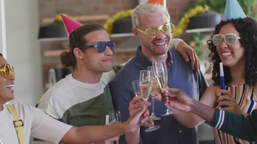 Grupo feliz de diversos amigos em chapéus de festa comemorando juntos, brindando com videira