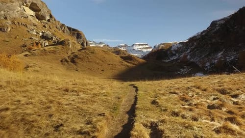 POV Walking auf dem Fall Field Path zum Bach und zu verschneiten Bergen