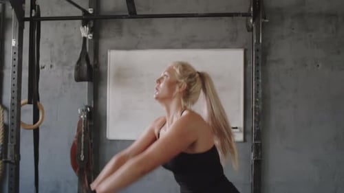 Sportswoman Doing Kettlebell Squats with Front Raises in Gym