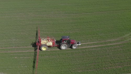 Tractor Sprays Fertilizers over Crop Field