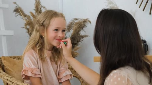 Mutter malt zu Hause die Lippen ihrer kleinen Tochter
