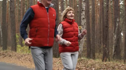Senior Couple Jogging Together Through Forest