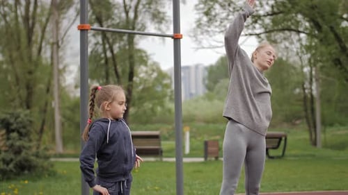 Mother and Daughter Doing Exercises on Open Air Sport Playground
