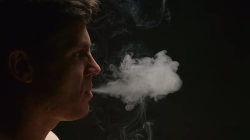 Man Exhaling Vapor Smoke in Dark Room