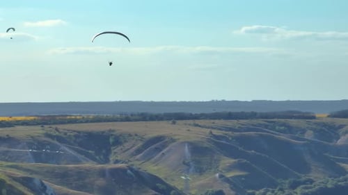 Aerial Footage of Flying Paragliders Against Green Hills and Sky