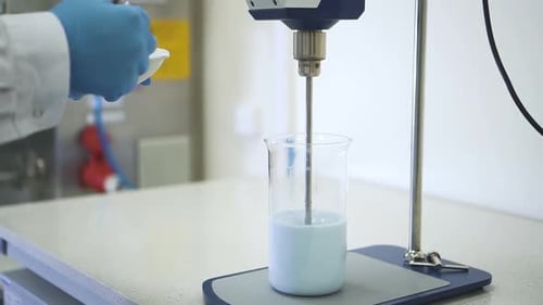 Lab Worker Mixing Light Blue Solution With Powder