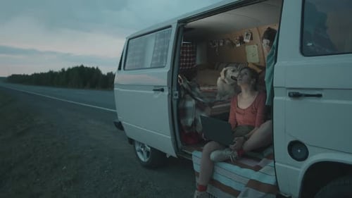 Woman and Dog Relaxing in Van at Sunset