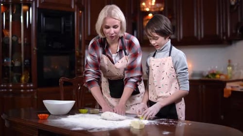 Son and Mother Having Fun Kneading Dough in Kitchen at Home