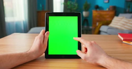 Closeup of Man Using Green Mockup Screen Digital Tablet Computer in Portrait Mode While Sitting