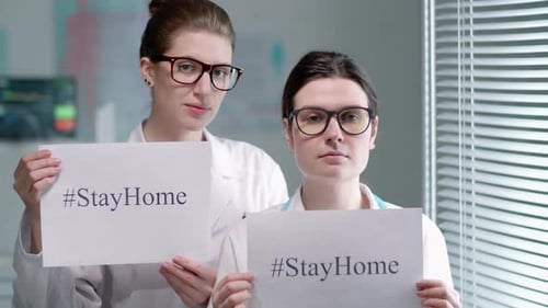 Two Doctors Holding #StayHome Signs in Hospital Setting