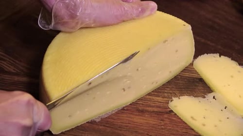 Restaurant Serving Man Cutting Off a Piece of a Cheese Head with a Knife