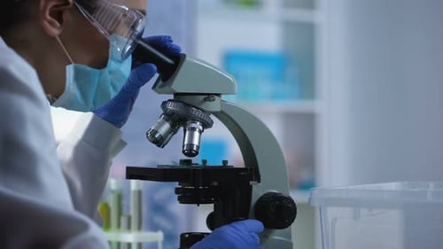 Scientist Inspecting Sample Through a Microscope