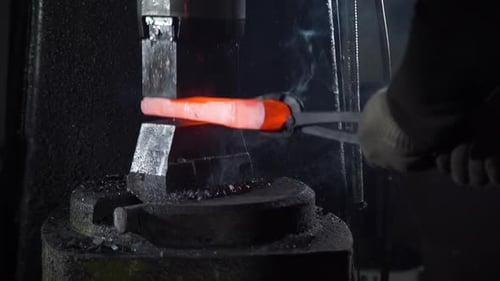Blacksmith Forging Glowing Metal on Anvil with Hammer