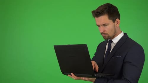 A Young Handsome Businessman Works on a Notebook - Green Screen Studio