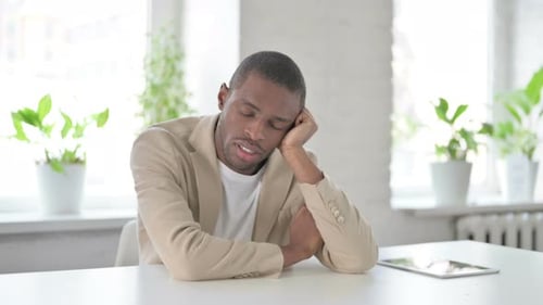 Sleepy African Man Taking Nap While Sitting in Office
