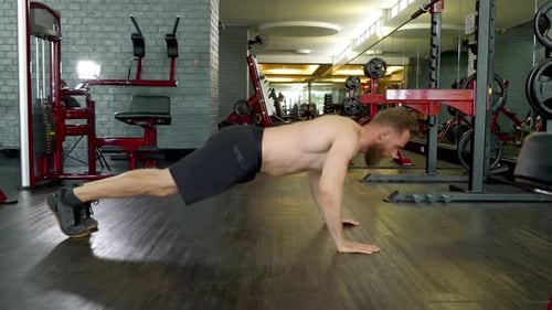 Athlet mit straffem Körper macht einen Liegestütz im Indoor-Fitnessstudio