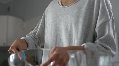 Young Adult Whisking Eggs in Glass Bowl