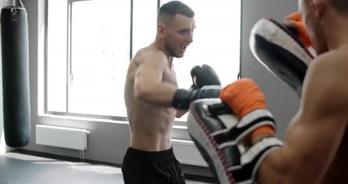 Steadicam Shot Kickboxer is Practising His Punches with Trainer in Slow Motion in the Gym Kickboxer