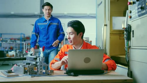 two asian coworker brainstorm explaining and solves the process of the cnc operate machine