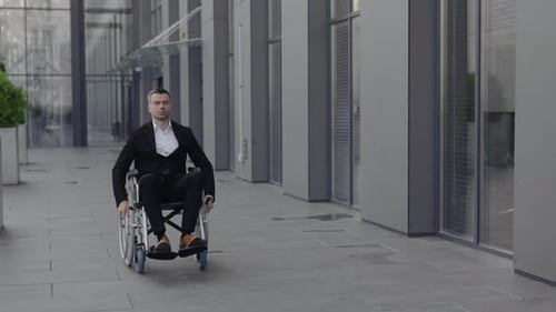 Handsome Businessman in Wheel Chair Looking Ahead While Going at Street