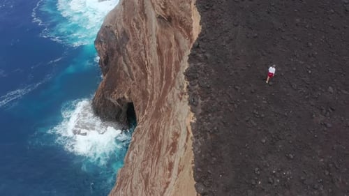 Coastal Cliffs and Person Exploring the Shore