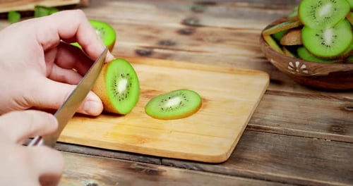 Slicing a Green Kiwi Fruit on a Cutting Board