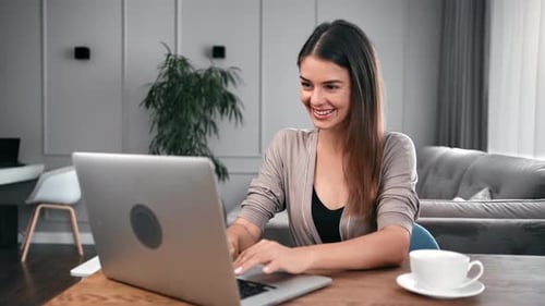 Woman Smiling and Typing on Laptop at Home