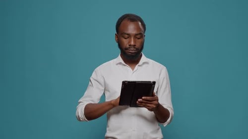 Young Adult Using Tablet Against Blue Background