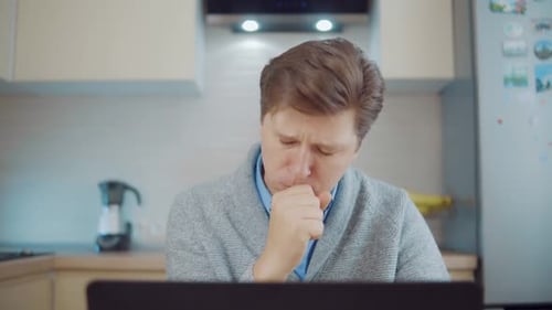 Adult Coughing at Home While Using Laptop