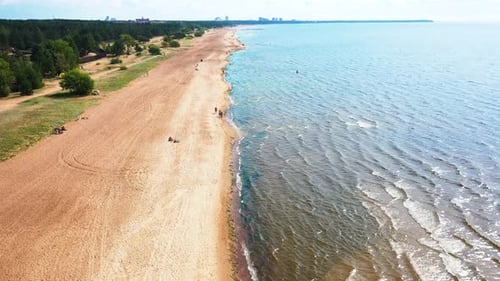 Flying Over The Beach With People Walking And Swimming In The Water
