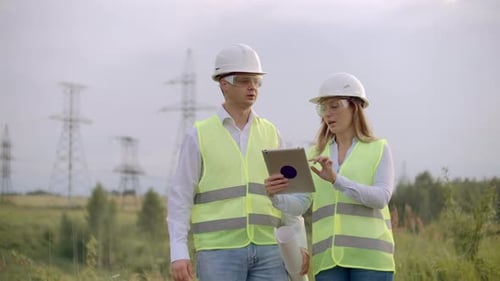 Engineering Working on Highvoltage Tower Check the Information on the Tablet Computer Two Employees