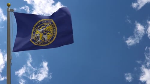 Waving Flag of Nebraska Against Clear Blue Sky