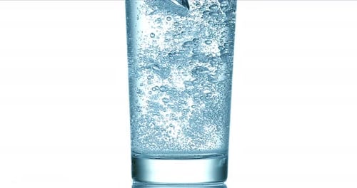 El agua se vierte en el vidrio sobre fondo blanco, cámara lenta 4K