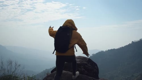 Randonneuse réussie bras ouverts au sommet d'une montagne.