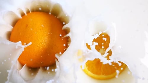 Two Parts of Orange Falling Down Into the Milk
