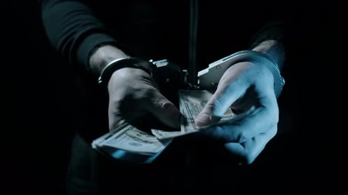 Hands in Handcuffs Holding Cash at Night