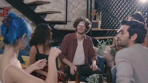 Friends Enjoying Game with Beer Bottles at Home Party
