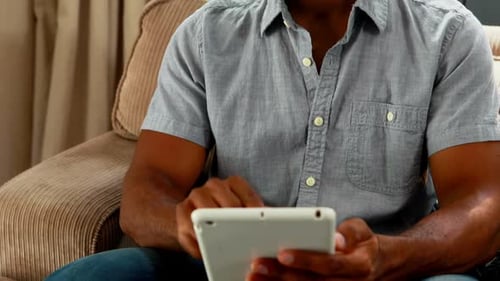 Handsome man using digital table in living room 4k