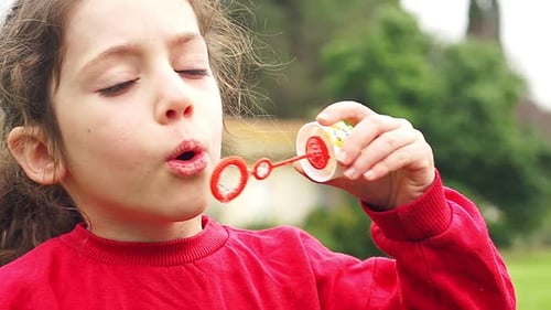 Girl Blowing Bubbles in a Green Garden