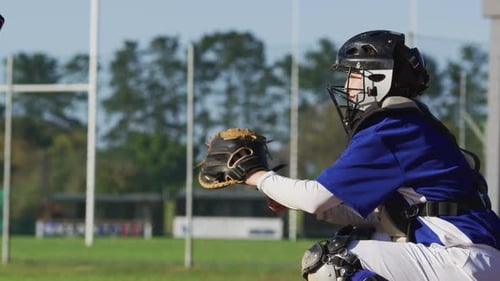 Kaukasische Baseballspielerin in Fängerposition fängt Ball auf Baseballfeld