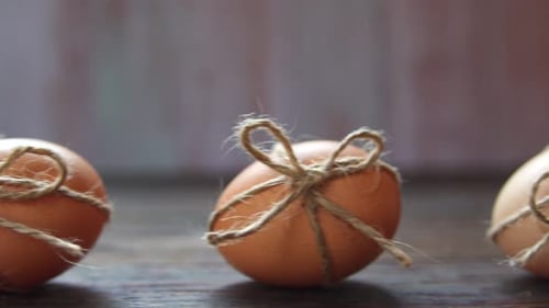 Close Up Shot of Chicken Brown Easter Eggs Decorated with Thin Rope in Blurred Wooden Background