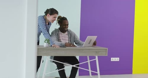 Positive Smiling Man and Woman Near Working Place with Laptop Cooperating in Office