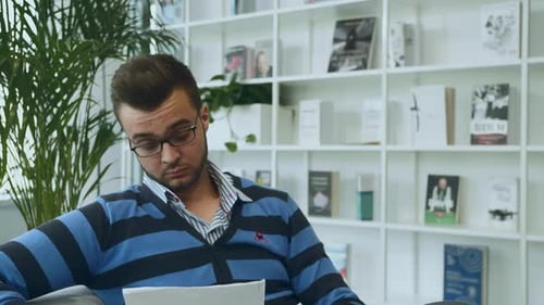 Un homme avec des papiers qui parle au bureau. Homme élégant adulte à lunettes assis sur un canapé avec des papiers et