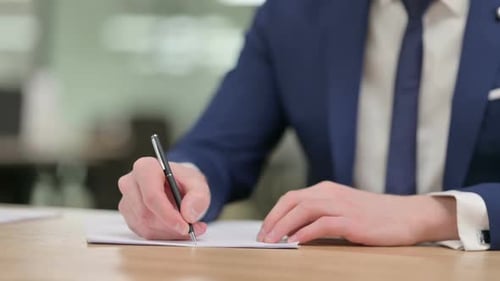 Close Up of Hands of Businessman Writing on Paper