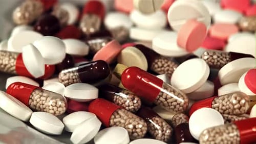 Various Capsules and Pills Fall Into a Heap on the Table