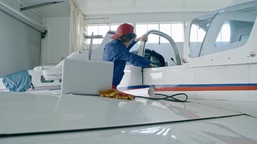 Female Engineer Using Laptop While Testing Airplane Engine