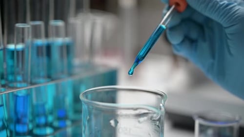 Dropping Blue Liquid into a Beaker in Laboratory