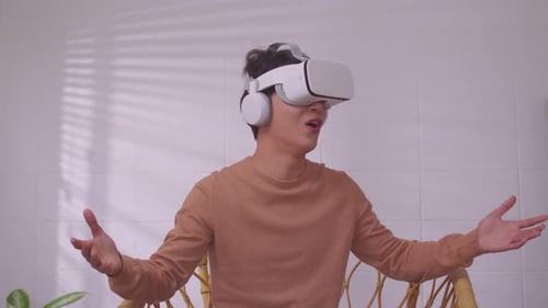 Asian man wearing virtual reality goggles in modern coworking studio.