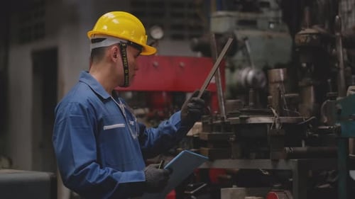 Factory worker technician or engineer with yellow helmet and blue uniform check the quality
