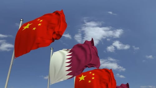 Waving Flags of Qatar and China Against Blue Sky